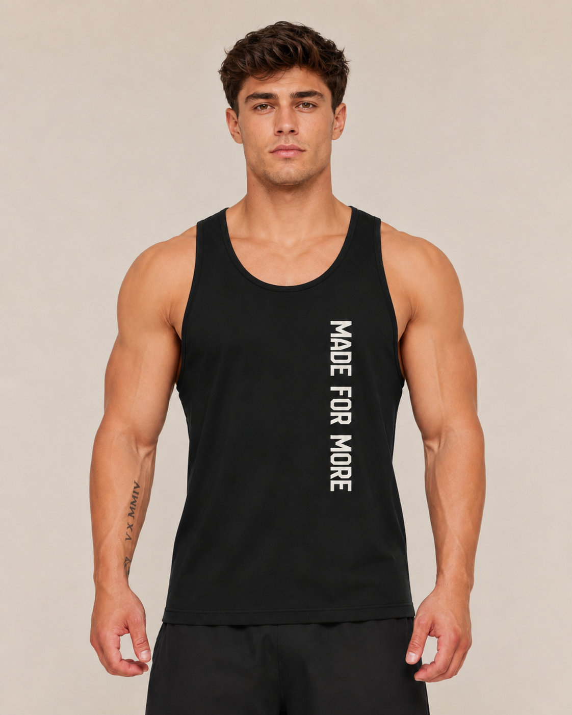 Man wearing a black tank top with 'MADE FOR MORE' text on a beige background